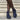 Navy blue suede ankle boots worn with black tights on a neutral background