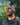 Man wearing a beige beanie with a logo, standing outdoors with trees in the background