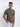 A tall and slim man in the studio standing in front of a light background. The smiling model is wearing an extra long slim dark grey t-shirt in a size medium. The tall dark grey t-shirt features a 3" longer body, 100% organic cotton, and is soft & preshrunk. The dark grey t-shirt is ideal for tall slim men 6'2"+.