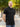 A tall and athletic man in a park standing on a path between trees. The smiling model is wearing an extra long slim black polo shirt in a size XL. The tall black polo shirt features a 3" longer body, 100% organic cotton, and is soft & preshrunk. The black polo shirt is ideal for tall slim men 6'2"+.