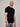 A tall and slim man in the studio standing in front of a light background. The smiling model is wearing an extra long slim black t-shirt in a size XL. The tall black t-shirt features a 3" longer body, 100% organic cotton, and is soft & preshrunk. The black t-shirt is ideal for tall slim men 6'2"+.