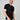 A tall and slim man in the studio standing in front of a light background with one hand in his pocket. The smiling model is wearing an extra long slim black v-neck t-shirt in a size XL. The tall black v-neck t-shirt features a 3" longer body, 100% organic cotton, and is soft & preshrunk. The black v-neck t-shirt is ideal for tall slim men 6'2"+.