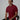 A tall slim man sitting in a studio and wearing a maroon medium tall polo shirt.