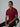 A tall slim man sitting in a studio and wearing a maroon medium tall polo shirt.