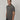A tall and slim man in the studio standing in front of a light background. The smiling model is wearing an extra long slim dark grey polo shirt in a size medium. The tall dark grey polo shirt features a 3" longer body, 100% organic cotton, and is soft & preshrunk. The dark grey polo shirt is ideal for tall slim men 6'2"+.