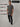 A head to toe shot of a tall slim man in a studio wearing a dark grey medium tall polo shirt.