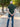 A shot from behind of a tall athletic guy in a park and wearing an XL tall slim dark pine polo shirt and showing the minimal Just Tall flag logo near the bottom of the side seam.