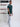 A head to toe shot of a tall slim guy  in a studio and wearing a dark teal medium tall slim t-shirt.