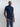 An upper body shot of a tall slim guy wearing a large tall midnight blue t-shirt, one hand in pocket.