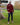 A head to toe shot of a tall athletic guy wearing an XL tall maroon long sleeve t-shirt, standing in a park and looking down at the Just Tall logo.