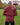 A shot from behind of a tall slim guy in a park wearing an extra long sleeve long sleeve tall t-shirt in dark orange.