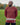 An upper body shot of a tall athletic guy standing in a park wearing a dark orange extra long tall long sleeve t-shirt and showig the the Just Tall minimalist monogram logo.