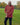A shot of a tall athletic guy in a park wearing a dark orange long sleeve tall t-shirt, looking down at the t-shirt logo.