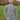 A tall and slim man standing in a park. The smiling model is wearing a light grey long-sleeve tall t-shirt. The tall light grey long-sleeve t-shirt features a 2.5" longer sleeves, 100% organic cotton, and is soft & preshrunk. The light grey long-sleeve t-shirt is ideal for tall slim men 6'2"+.