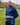 An upper body shot of a tall athletic guy standing in a park wearing a navy extra long tall long sleeve t-shirt and showing  the Just Tall minimalist monogram logo.