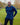 A tall athletic guy wearing a long sleeve navy tall t-shirt and smiling in a park with hands behind back.