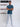 A head to toe shot of a tall slim guy  in a studio and wearing a petrol medium tall slim t-shirt, arms folded.