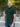 A tall and athletic man in a park standing on a path between trees. The smiling model is wearing an extra long slim dark pine polo shirt in a size XL. The tall dark pine polo shirt features a 3" longer body, 100% organic cotton, and is soft & preshrunk. The dark pine polo shirt is ideal for tall slim men 6'2"+. Buy 2 Save 10%, Buy 4 Save 15%, Buy 6 Save 20%.