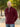 A tall slim guy wearing an XL tall maroon quarter zip sweatshirt in a park with his hands behind his smiling.