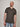 A tall and slim guy smiling in the studio and wearing a dark grey XL tall slim v-neck t-shirt.