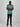 A head to toe shot of a tall and slim guy in the studio, hands folded and wearing a teal L tall slim v-neck t-shirt.